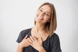 beautiful-positive-friendly-looking-young-mixed-race-woman-with-lovely-sincere-smile-feeling-thankful-grateful-showing-her-heart-filled-with-love-gratitude-holding-hands-her-breast