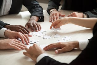 Close-up-of-multiethnic-team-solving-blank-puzzle-game