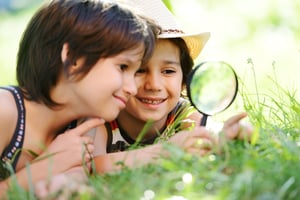 Happy kid exploring nature with magnifying glass