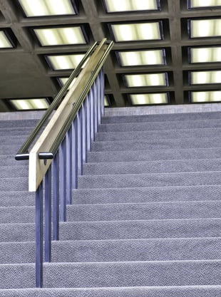 On your way to the top Handrail above carpeted stairway with fluorescent lights overhead (selective focus)