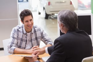 Salesman showing client where to sign the deal at new car showroom
