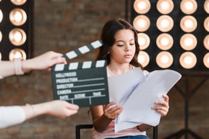 hand-holding-clapper-board-front-girl-reading-scripts-studio