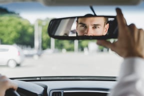 handsome-male-driver-adjusting-rearview-mirror-car