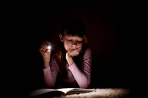 little-girl-is-reading-book-with-flashlight-dark-room-night