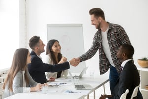 smiling-businessman-welcoming-new-partner-group-meeting-with-handshake