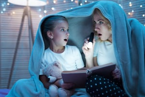 woman-girl-are-reading-book-with-flashlight