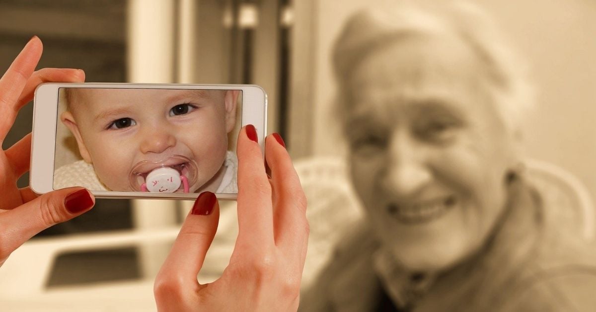 hand taking a photo of an older woman with a phone baby's face appears on screen