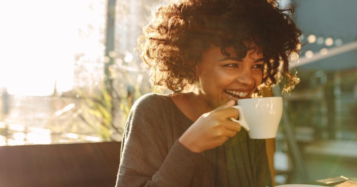 Woman of color drinking cup of coffee happily
