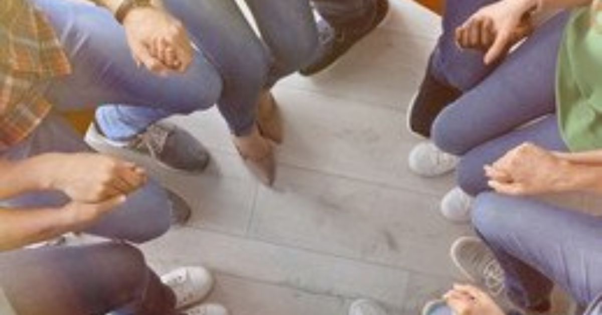 group sitting close together in a circle looking at their feet