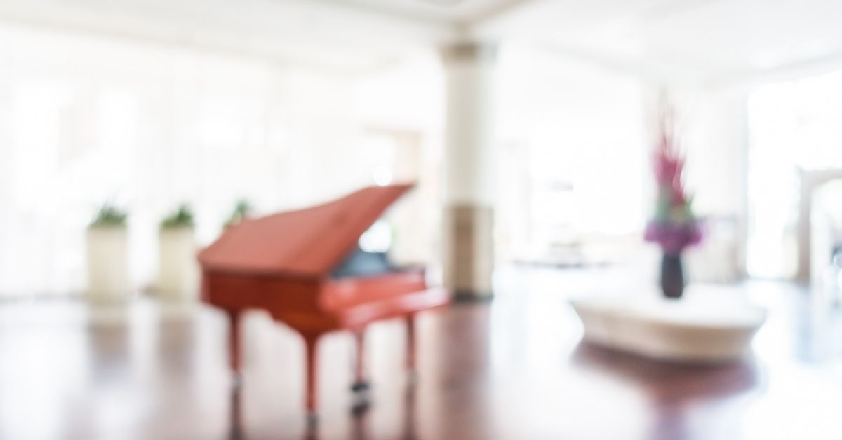 blurred image of a grand piano in a large bright room