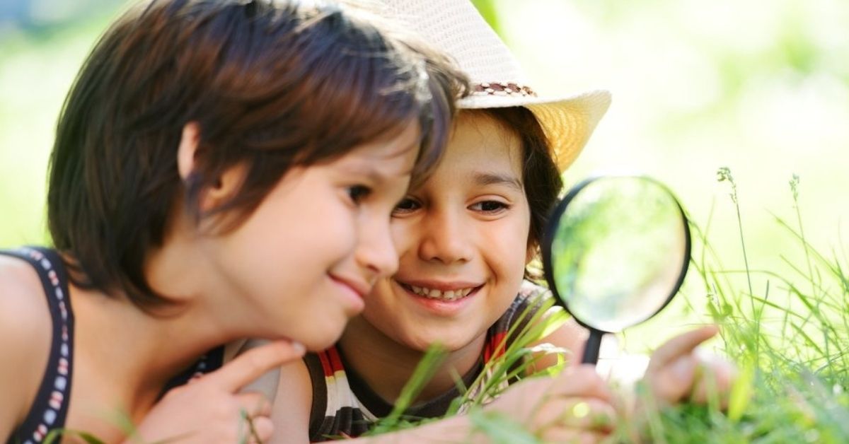 Happy kid exploring nature with magnifying glass