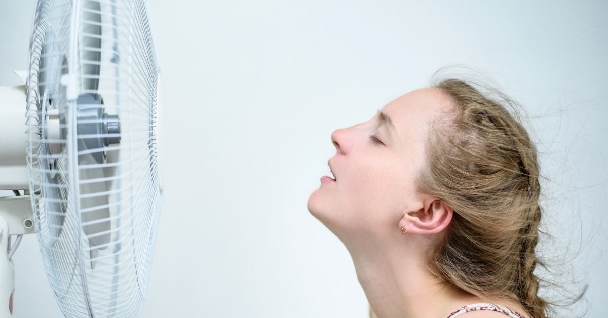 woman in front of blowing fan cooling off