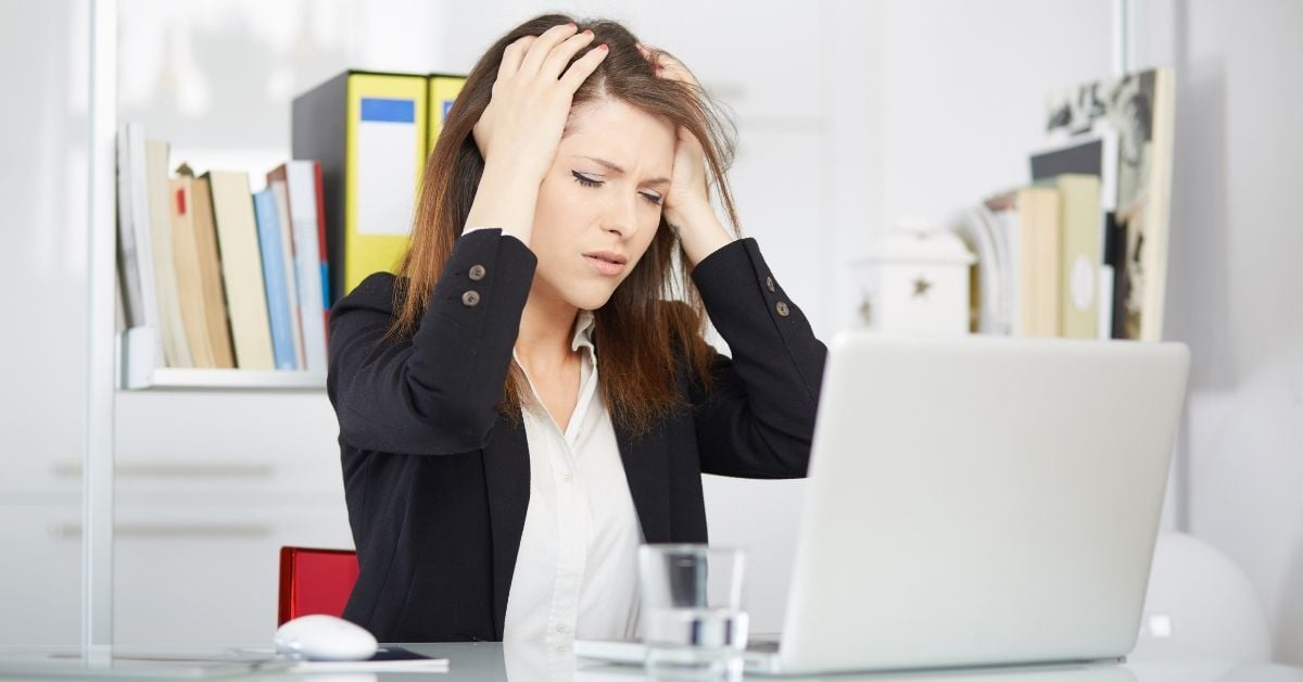 Stressed woman with hands run through hair sitting at desk