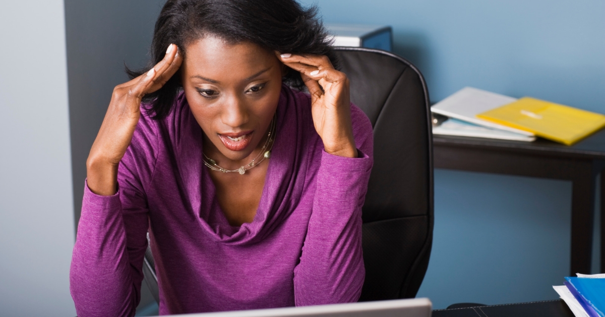 Woman very frustrated with hands on her head looking at computer screen