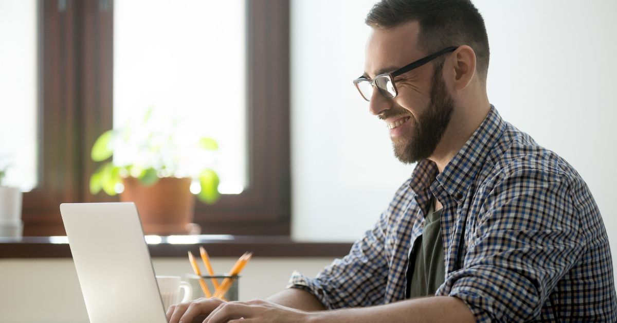 Person working at their desk, probably at a home office, typing on a laptop