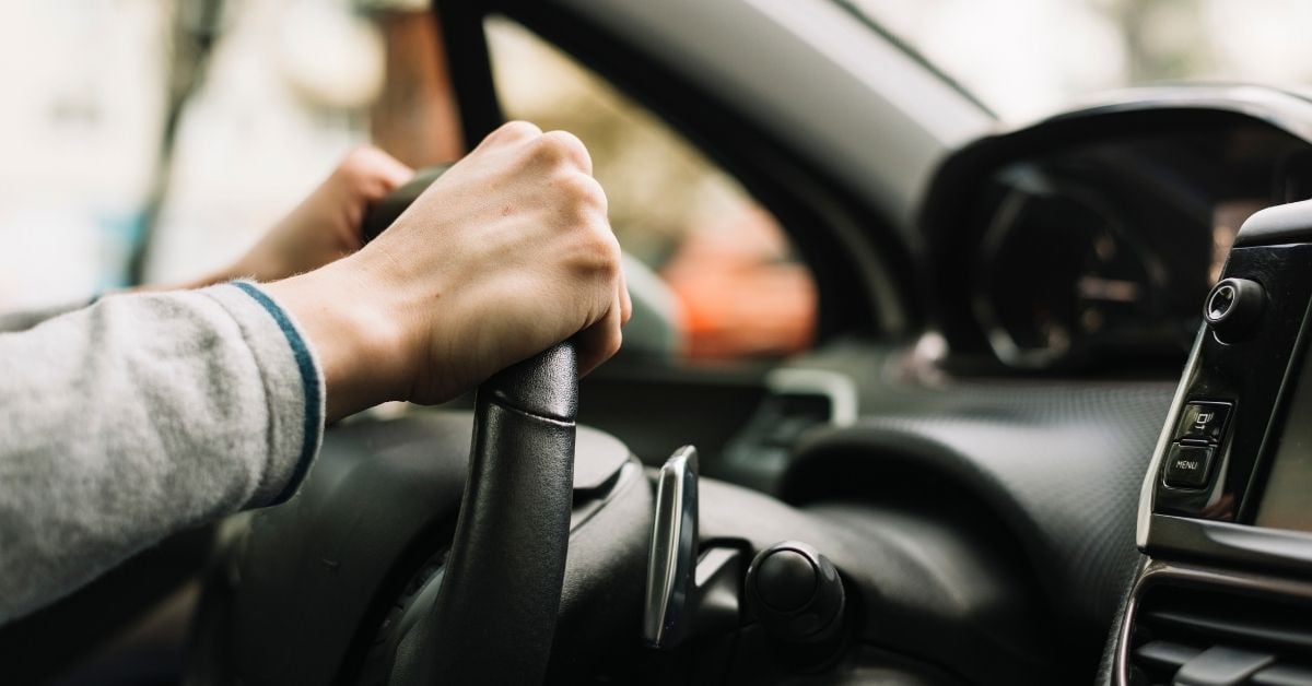 close up person driving hands on wheel