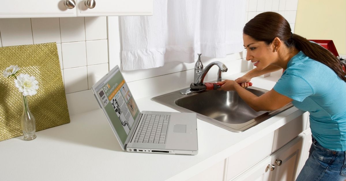 woman trying to fix a sink by using her computer