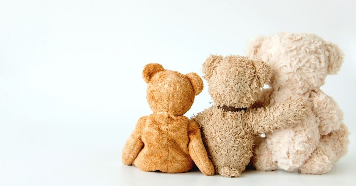 three teddy bears sitting in a line hugging with one arm looking off into the distance