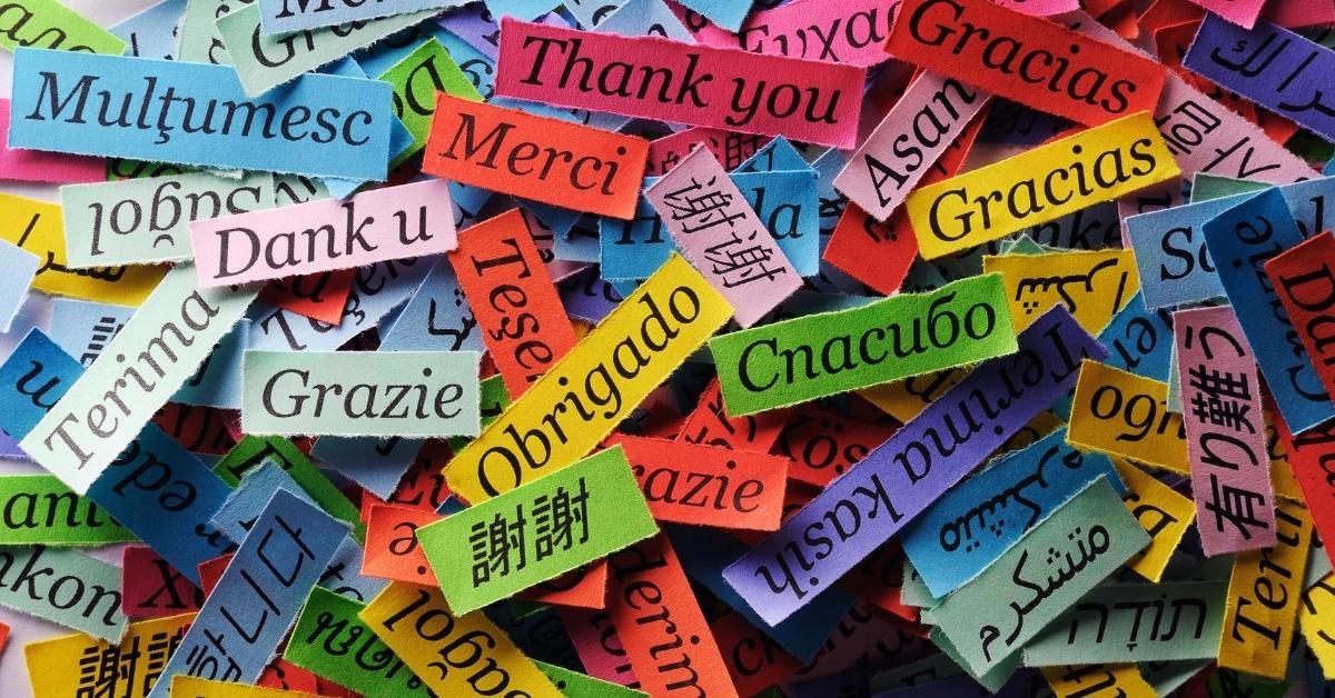 "Thank you" in various different languages written on colorful paper in a pile