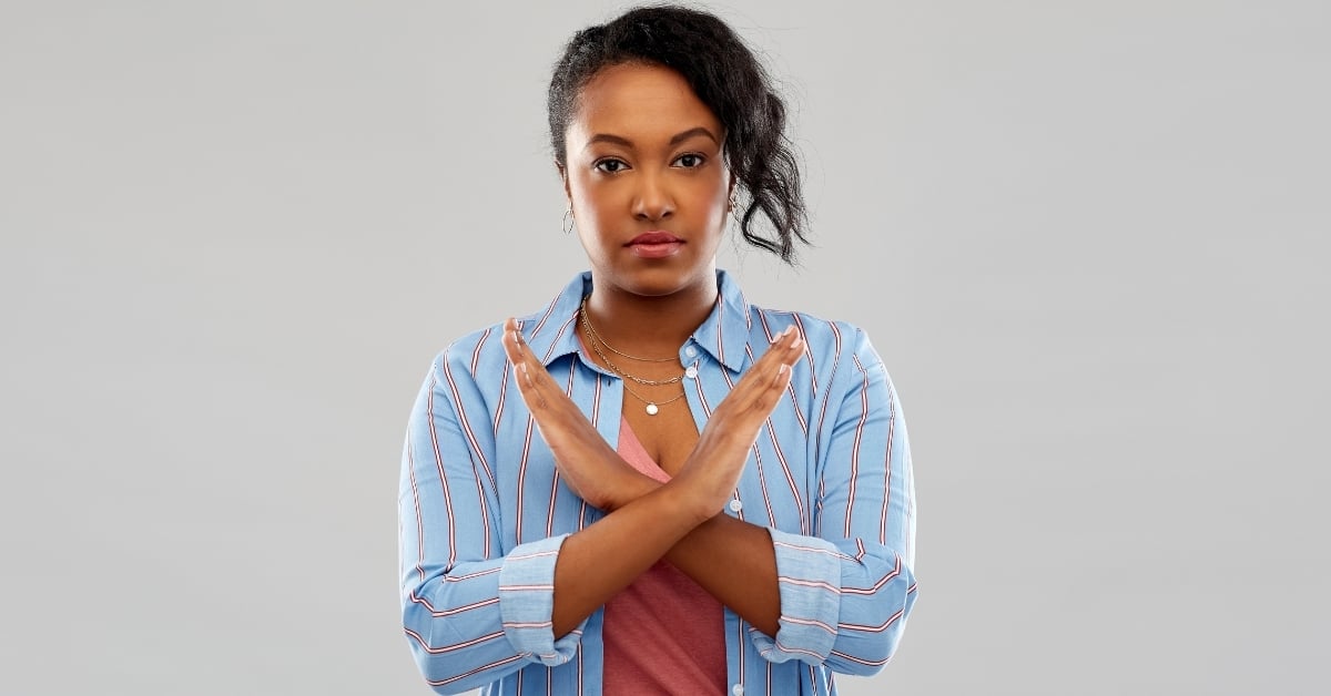 Woman of color crossing her arms in front of her chest to signify 'no'