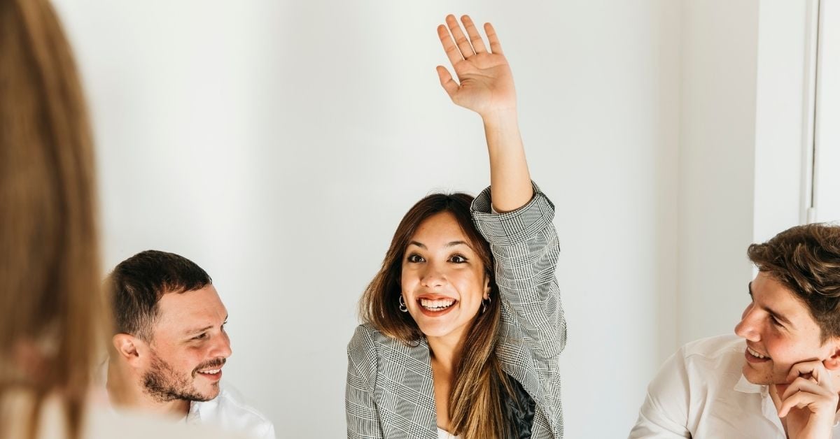 woman raising her hand to ask a question