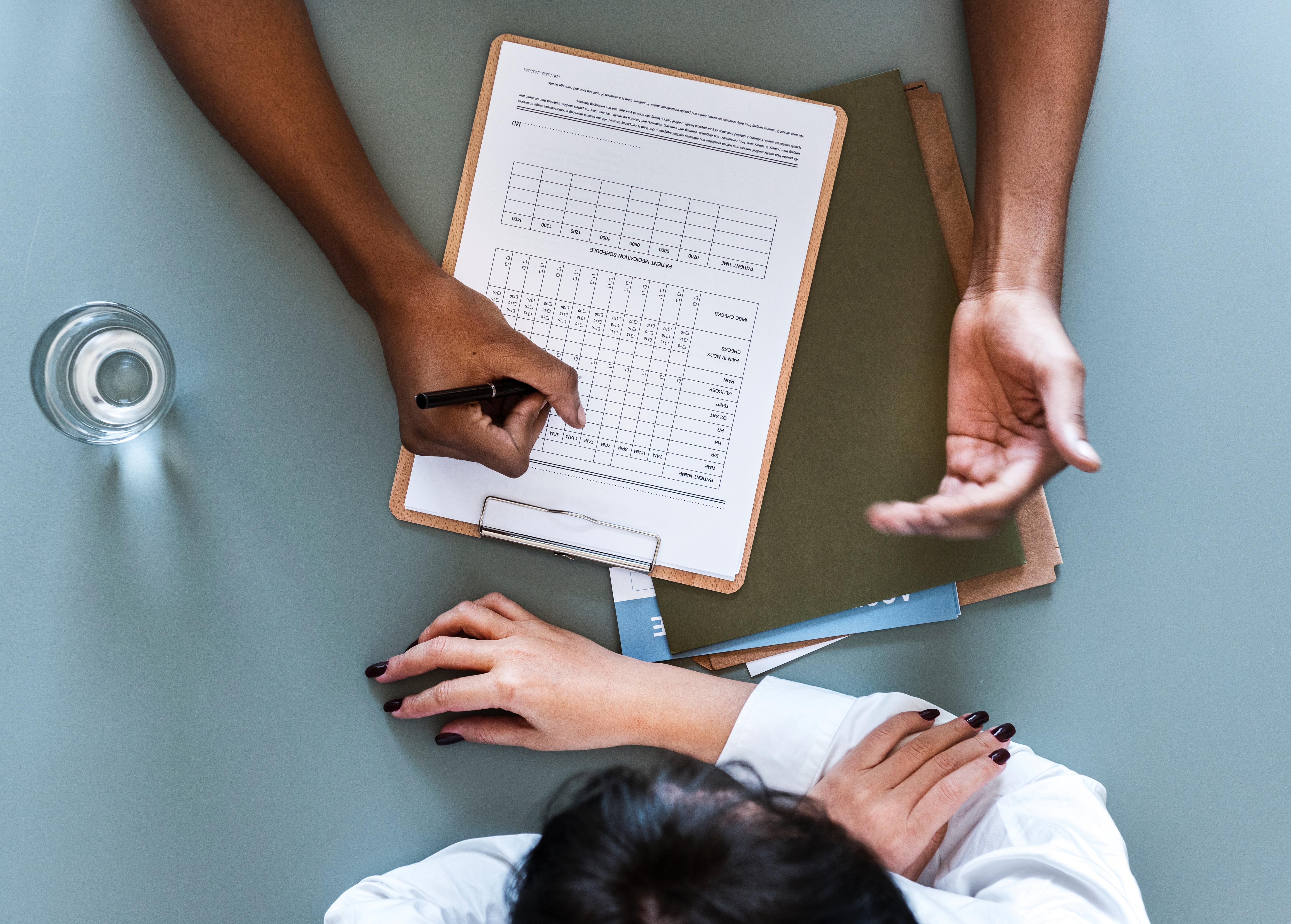 aerial-view-doctor-writing-patient-daily-report-checklist - re-touch 1