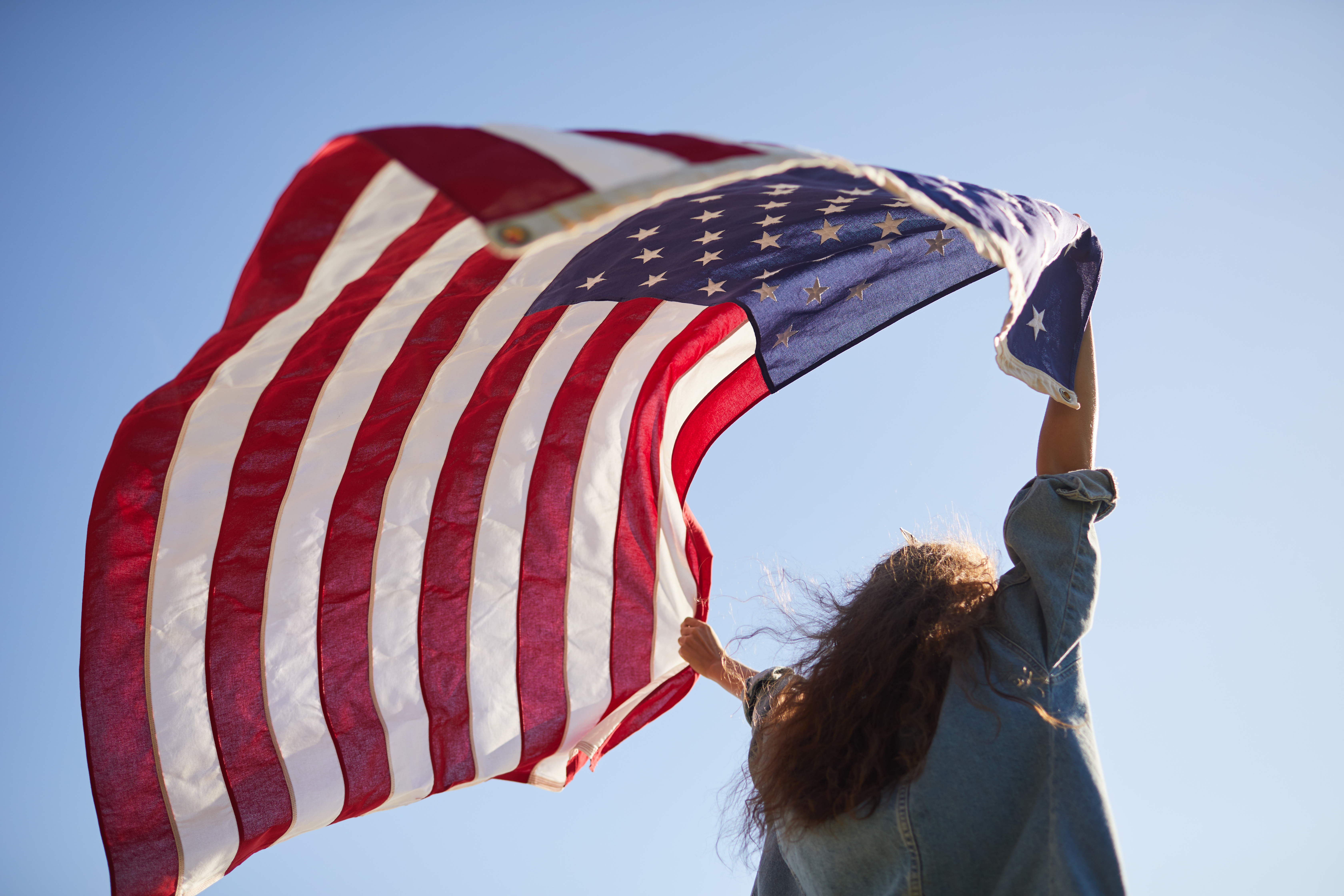 woman holding American flag in the wind 