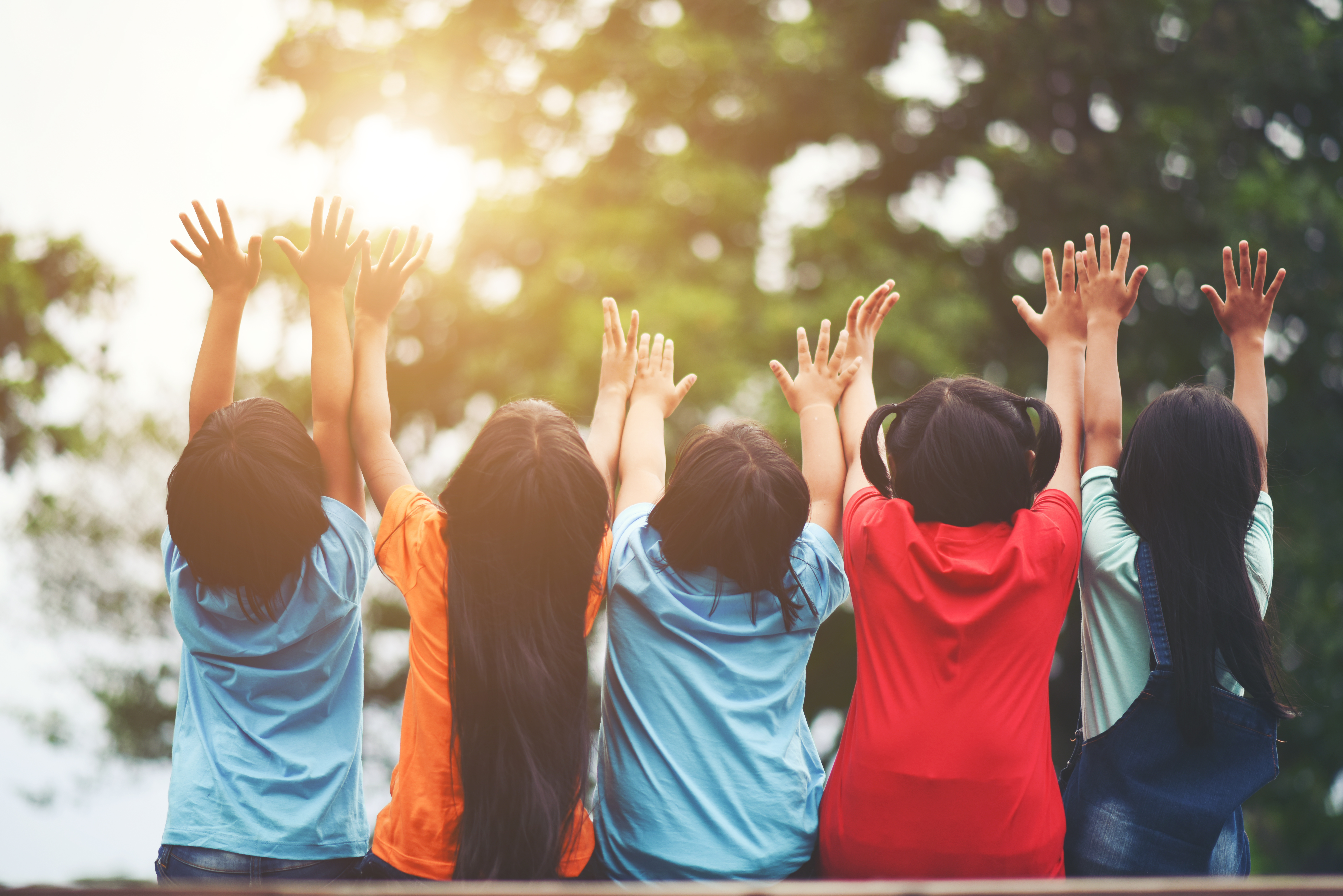 kids sitting with hands raised 