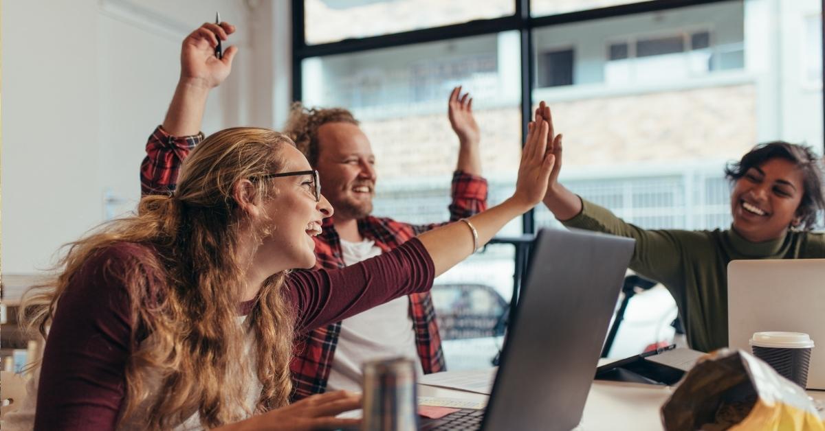 three coworkers celebrating with a high five